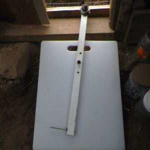 Self latching chicken door made of a cutting board. Swing arm of metal part from an EZ-up frame. This is significant to us, as we are full time crafts people and the folding tent covers are a big part of our lives. Counter weights of washers, and bolt pin.