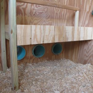 PVC pipes with covers caulked into the walls for access to eggs. I think I may try putting some wicker baskets under the holes to see if the chickens use them for nests. Otherwise our old nest boxes will fit under the platform once I cut off the sloped top.