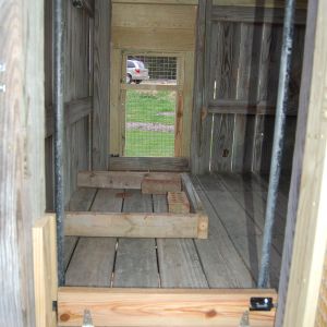 Originally we had the hole in the floor for the ramp here (edged by the 2x4's to hold back the bedding).  We ended up moving the hole and now the feeder is hanging above this location.  We put the hole under the poop board - works out perfectly!