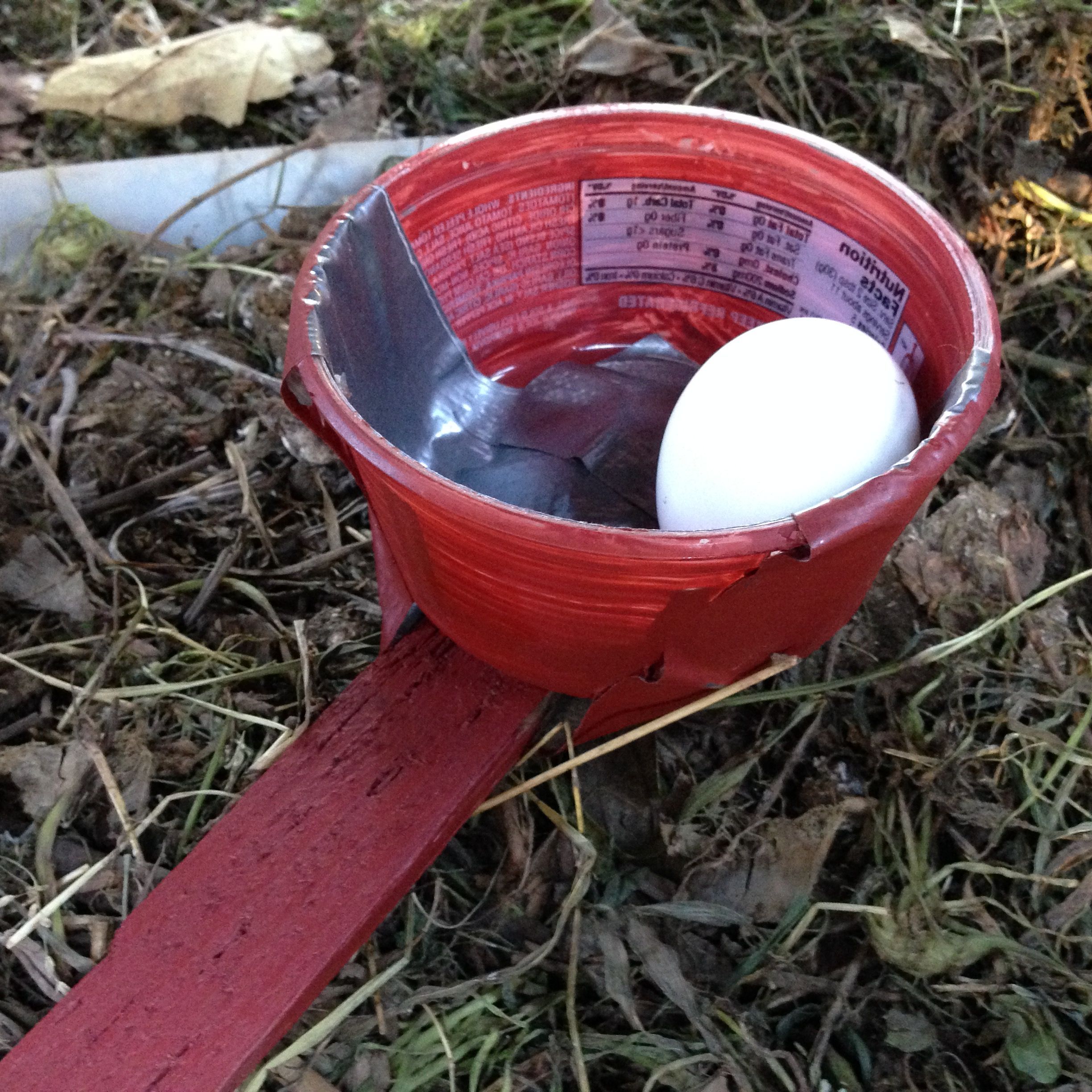 My McGyver tool for collecting eggs from the other side of the coop! Made from a leftover strip of wood and a plastic container, and some elegant duct tape. Barn red paint fixes everything.
