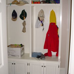 A built in coat closet with storage bench.