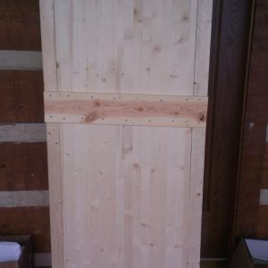 My door-almost finished. It is clamped here since I used wood glue under the cross boards. I also have to run boards down the side, but my lumber got wet and I have to dry it out first.