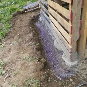 We laid stone footers under the walls and wire in the trench across the pallets.