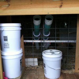 Center door, a wire divider is between the two feeders to separate the meat birds from my layers.  Stacked white buckets supply water to the nipples on the PVC