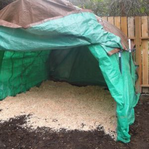Large heavy tarp attached with bungee cord and a bag of White Pine shavings.