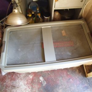 A 50 gal plastic tub with the top of the lid cut out and wire mesh to keep bugs and predators out. Heat supplied by a solid mounted 250w heat lamp and a flip top feeder.