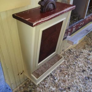 Wall mount chicken feeder. Purchased feeder shell on ebay and added trim pieces, stamped tin front, removable top (old baseboard material) with decorative handle (furniture piece).