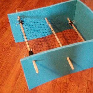 Deer netting added to dowels with clips to keep heating pad from slipping down through dowels when chicks climb on top of it.