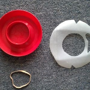 Cut a circle from the plastic milk carton that's large enough to cover and extend about 1/4th inch over the bottom of the waterer. Trace and cut out the center of the plastic circle to fit over the waterer base. Cut a slot out on one side of the circle, and two notches opposite each other as shown.
