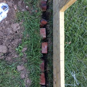 An 8 inch trench dug all the way around the run. We ran the wire to the bottom bunched the wire at the bottom. We then used recycled bricks wedged in the trench and covered with dirt. We have raccoon and possums in the country.