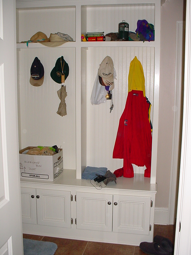 A built in coat closet with storage bench.