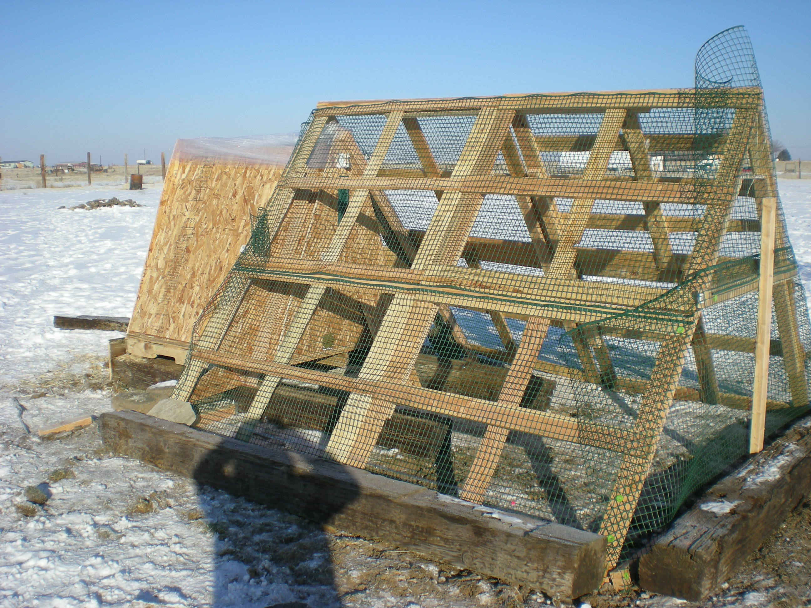 A closer look at the coop and the run.  We still need to put the shingles on, cut the fencing back where it is sticking up.  The ground was too hard to dig down so we have put rocks and railroad ties to deter any predators.  The chickens are enclosed at night and during the day my black lab wonders the 2 acres that are totally fenced in so hopefully predators won't be a problem, we will see.  It looks rough but it is a work in process...