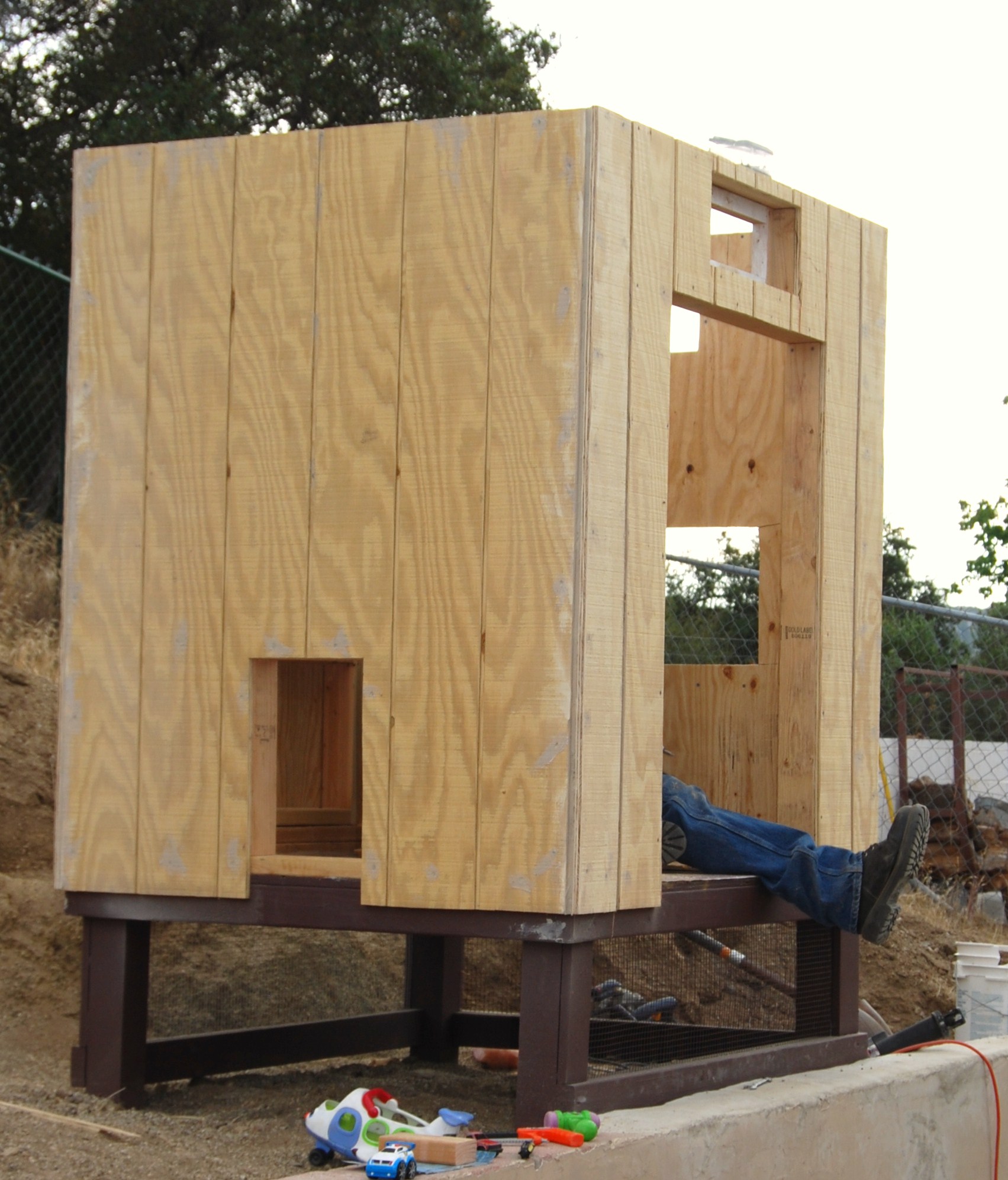 Coop with siding. Vent/windows up top, nest box in back, large door for cleaning, and ramp door facing camera.