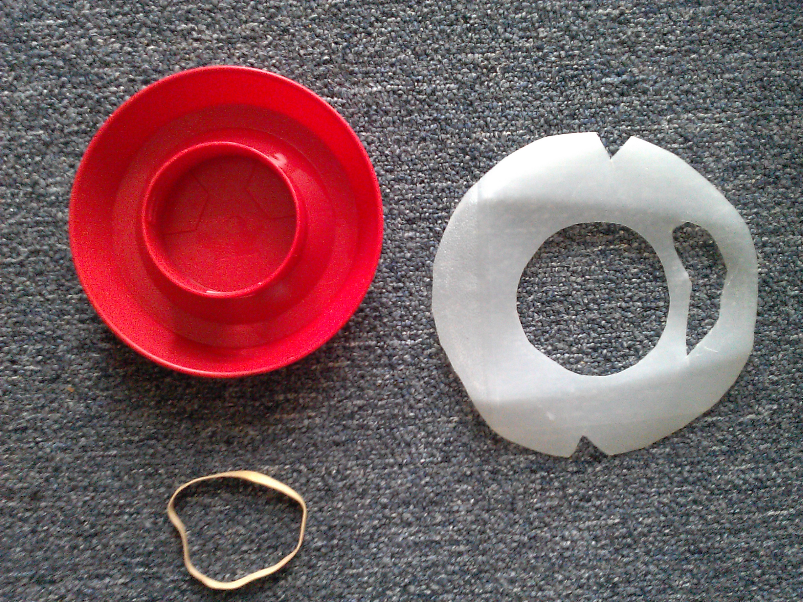 Cut a circle from the plastic milk carton that's large enough to cover and extend about 1/4th inch over the bottom of the waterer. Trace and cut out the center of the plastic circle to fit over the waterer base. Cut a slot out on one side of the circle, and two notches opposite each other as shown.