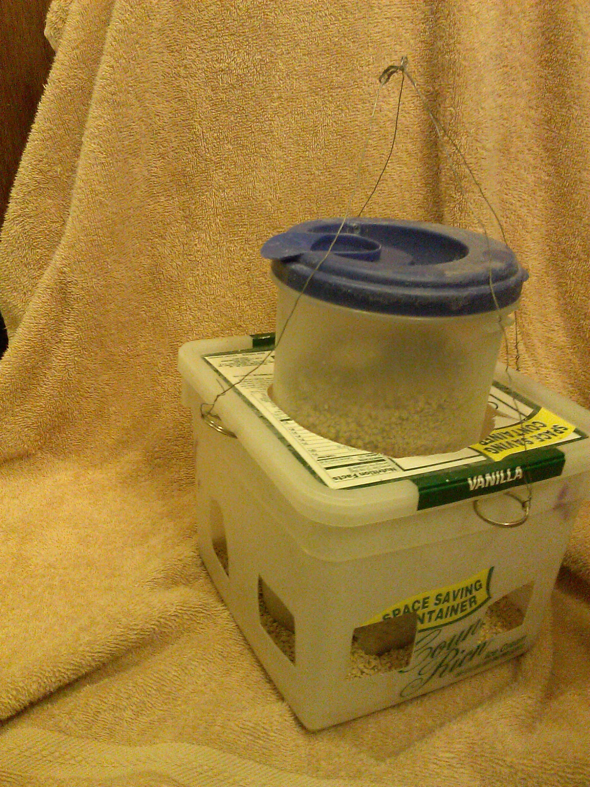 DIY No Waste Chick Feeder made from ice cream bucket, plastic pitcher, four key rings, and wire. Cut handle off pitcher. Cut circle in lid of ice cream bucket to fit pitcher.