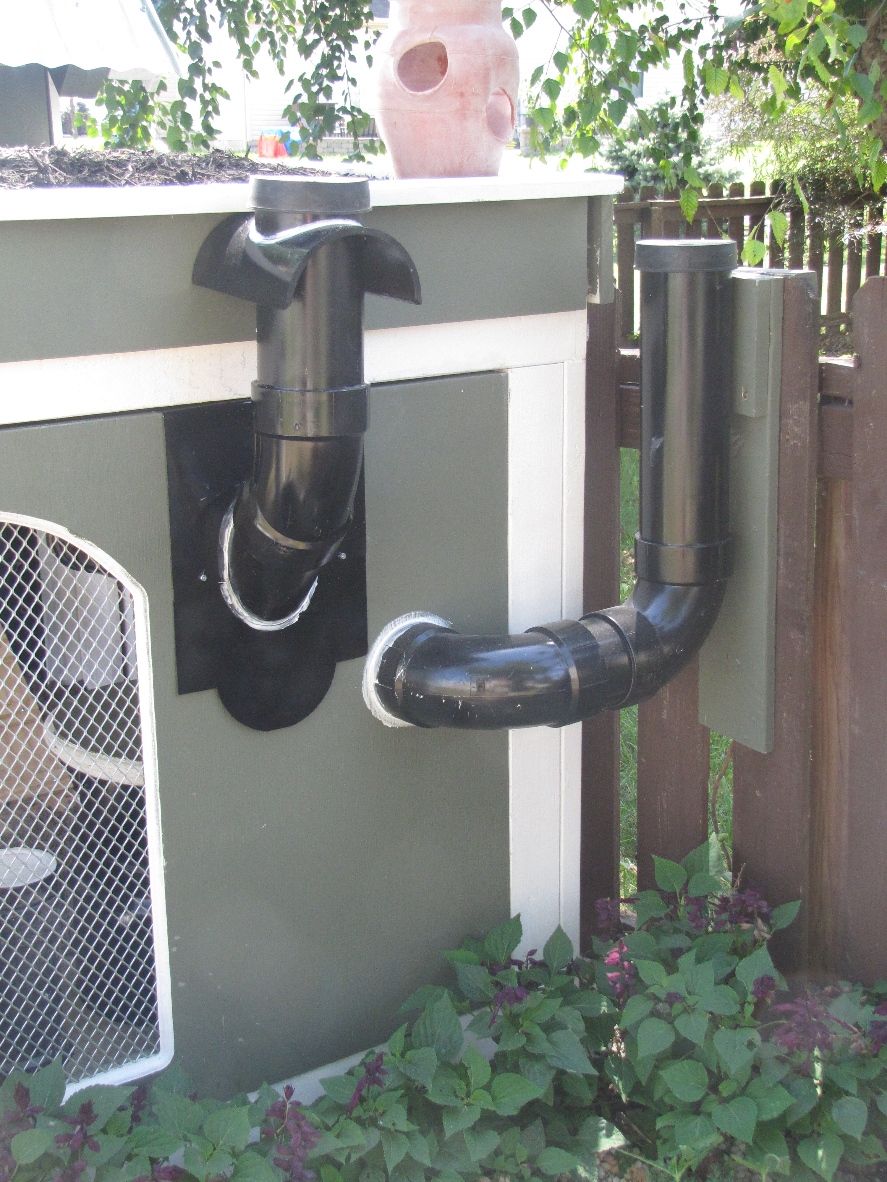 Exterior view of feed and water system. 4" pipe adjacent to the fence is for water, the next 4" pipe over is for feed, this makes for easy access as we replenish supplies