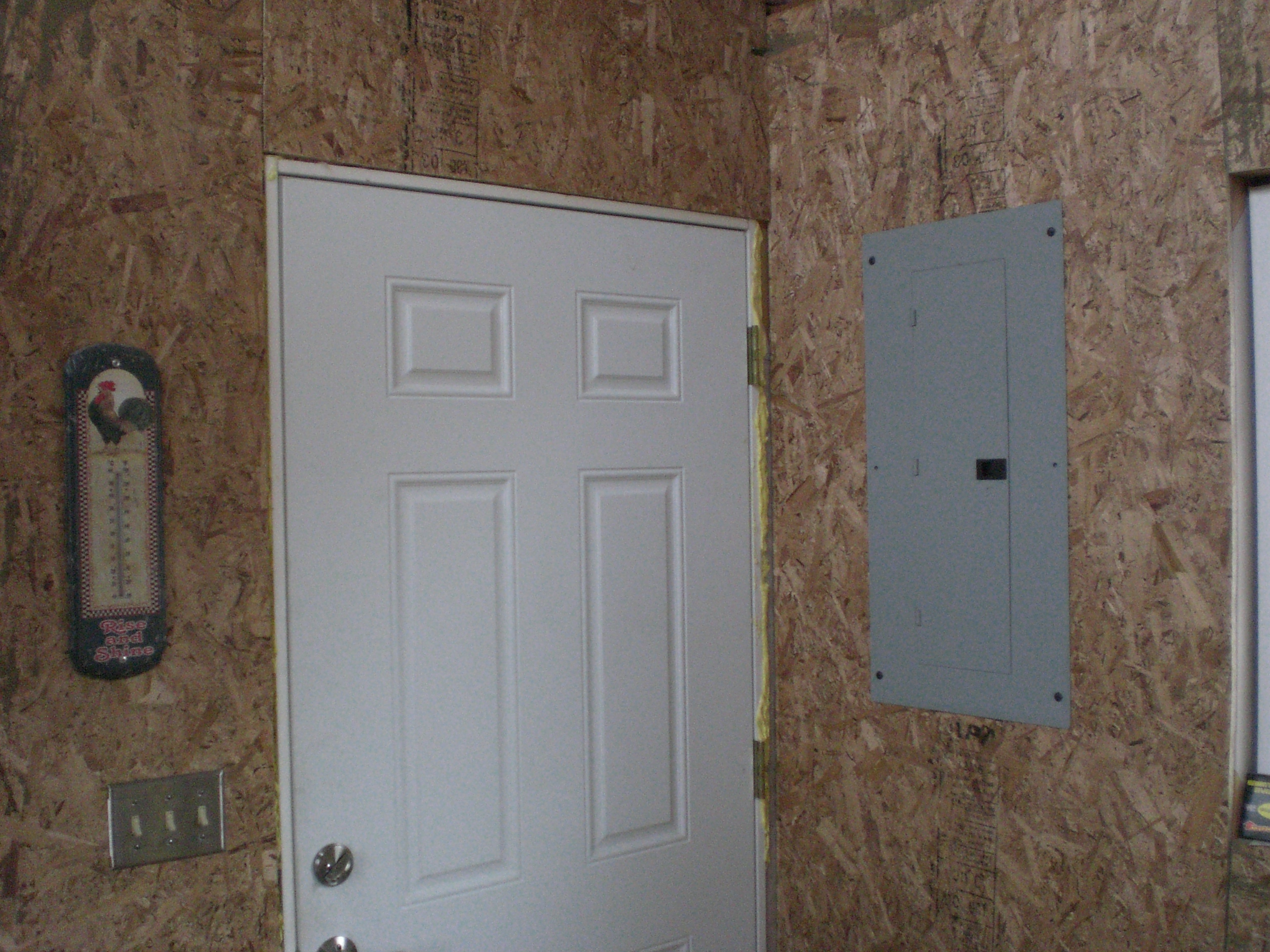 Front door.  Note the 200 amp service panel.  I was fortunate enough to get this off ebay for $25, and it takes the same breakers as the panels for the house and garage.  I plan on connecting with 2 gauge wire so it will be downgraded to 100 amps, but plenty enough power for a chicken house. 8)