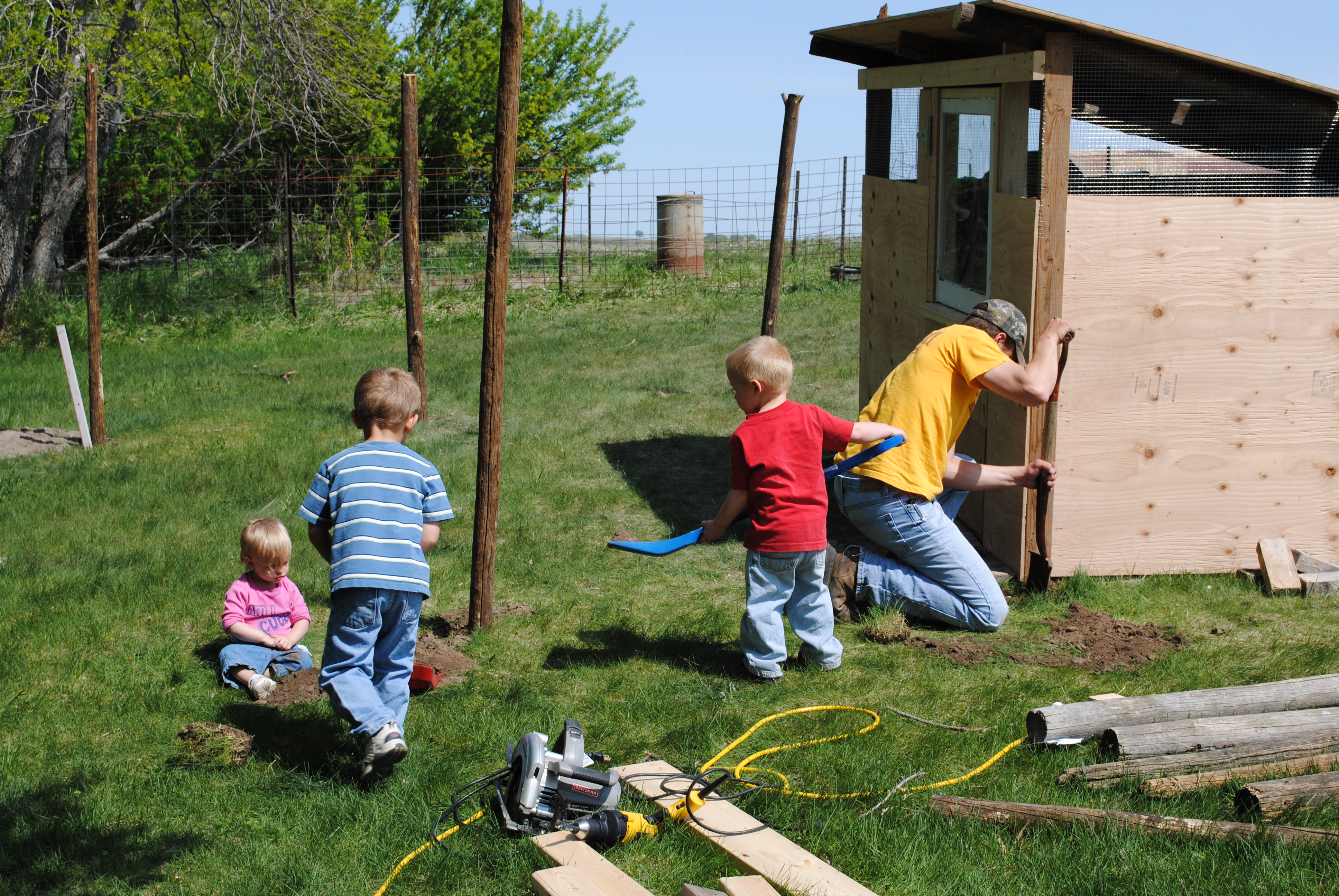 Here are my 3 kiddos and Daddy digging post holes for the run. Dad could hardly get the post holes dug before the kids would try to help fill them back in.