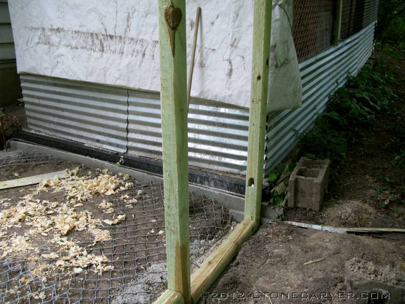 I had a lot of long pieces of old threaded rod, so they are set in the concrete foundation and the timbers are drilled out and mounted over those, with nuts and washers locking them in place. In addition, the timbers are glued down with construction adhesive.

In this shot you can see the trench drain. The old run has a concrete floor, and we hose it down twice a year, so that drain will (I hope) prevent the new section from getting too muddy.