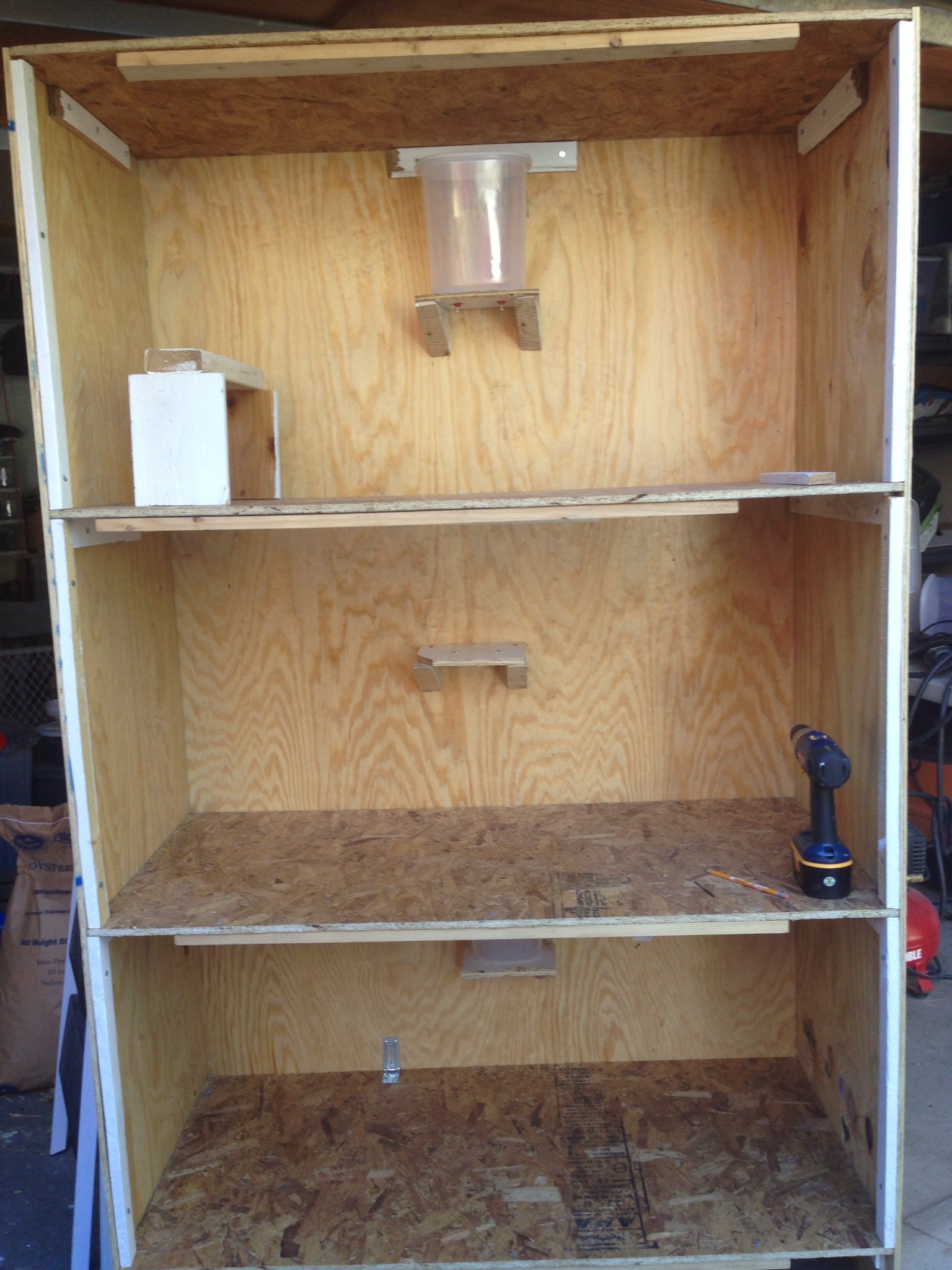 Installed shelves in each compartmeng that the nipple watering system will sit on. Used clear plastic containers from Walmart.