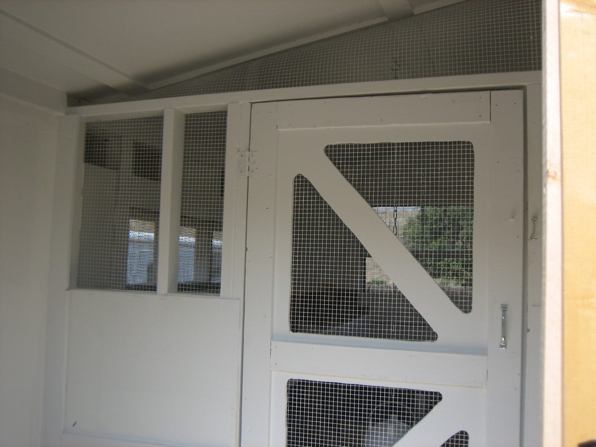 Looking into the coop from the storage area.  I did not have much door experience, so after looking at many doors on BYC, I came up with this idea for a screen door.  It is cut out of 1/2" pressed wood and reinforced with ripped 2x4's and covered in hardware cloth.