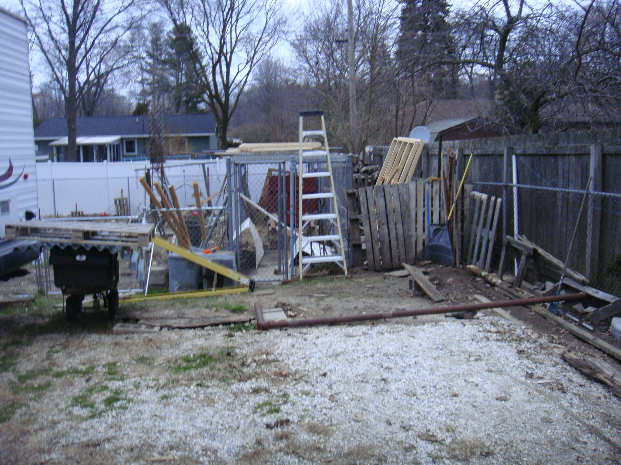 Looking north at the south end of the run. Ladder leaning on run top, framework for roof at side and on top of run. Constructed four sections 8 x 7 ft  of 2x4 s to attach Ondura roofing to and ptovide for pitch of about 3 -1.  Joists at 2' on center . Run is 6' W  x 30' L x 6' H Chain link wire. Concrete floor. Posts are 2 " Horizontal supports are 1 1/2' D. We had a Malmute and planned to breed her but she was discovered to have displasia, ruling out breeding. She was a great family dog for  almost 12 years.