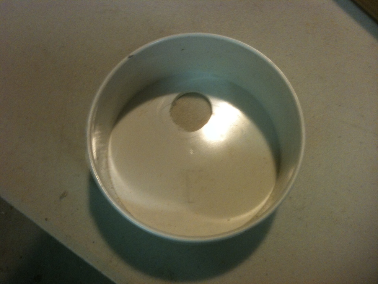 Materials needed:  1- 4" PVC (DWV) sanitary tee, a length of 4" DWV (whatever length you desire, 2- 4" DWV Flat end caps, 1- Clean-out fitting with cap, 1- toilet fill valve.

1. Drill a 1" hole in one of the end caps. Center of hole is 1" from edge of cap.