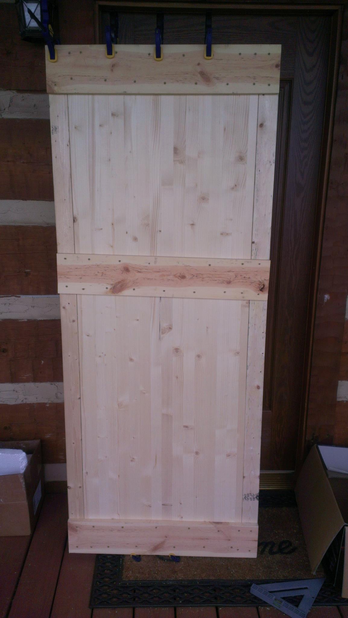 My door-almost finished. It is clamped here since I used wood glue under the cross boards. I also have to run boards down the side, but my lumber got wet and I have to dry it out first.