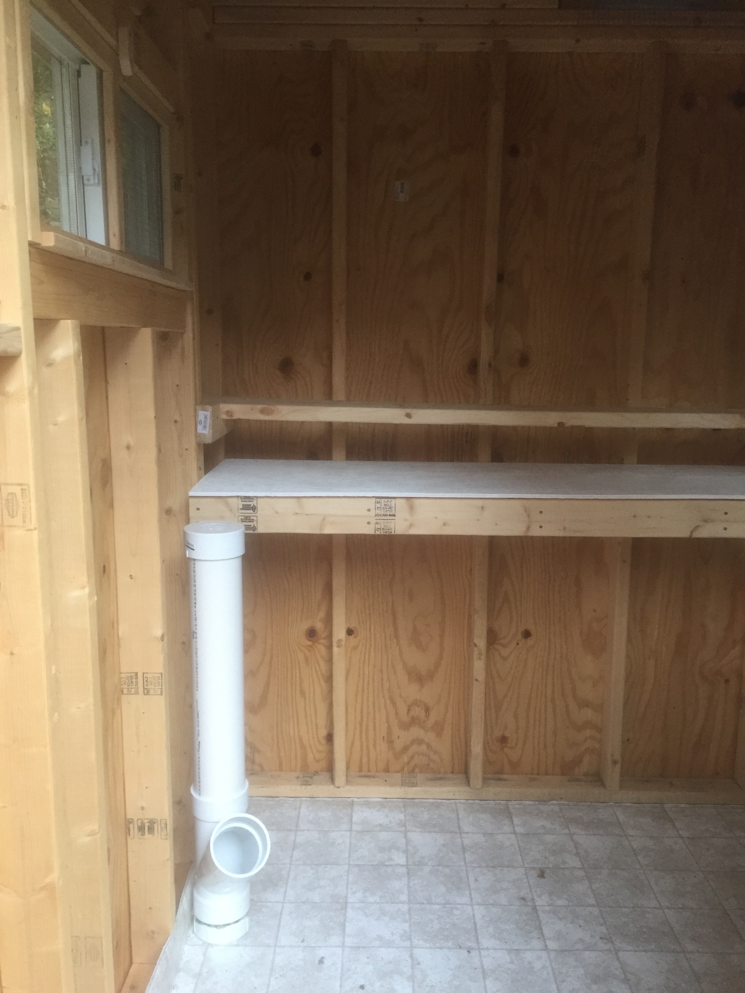 Poop board and roost bar across the back of the shed and first DIY PVC feeder sitting in front.  We ended up mounting a few of these along the left wall.