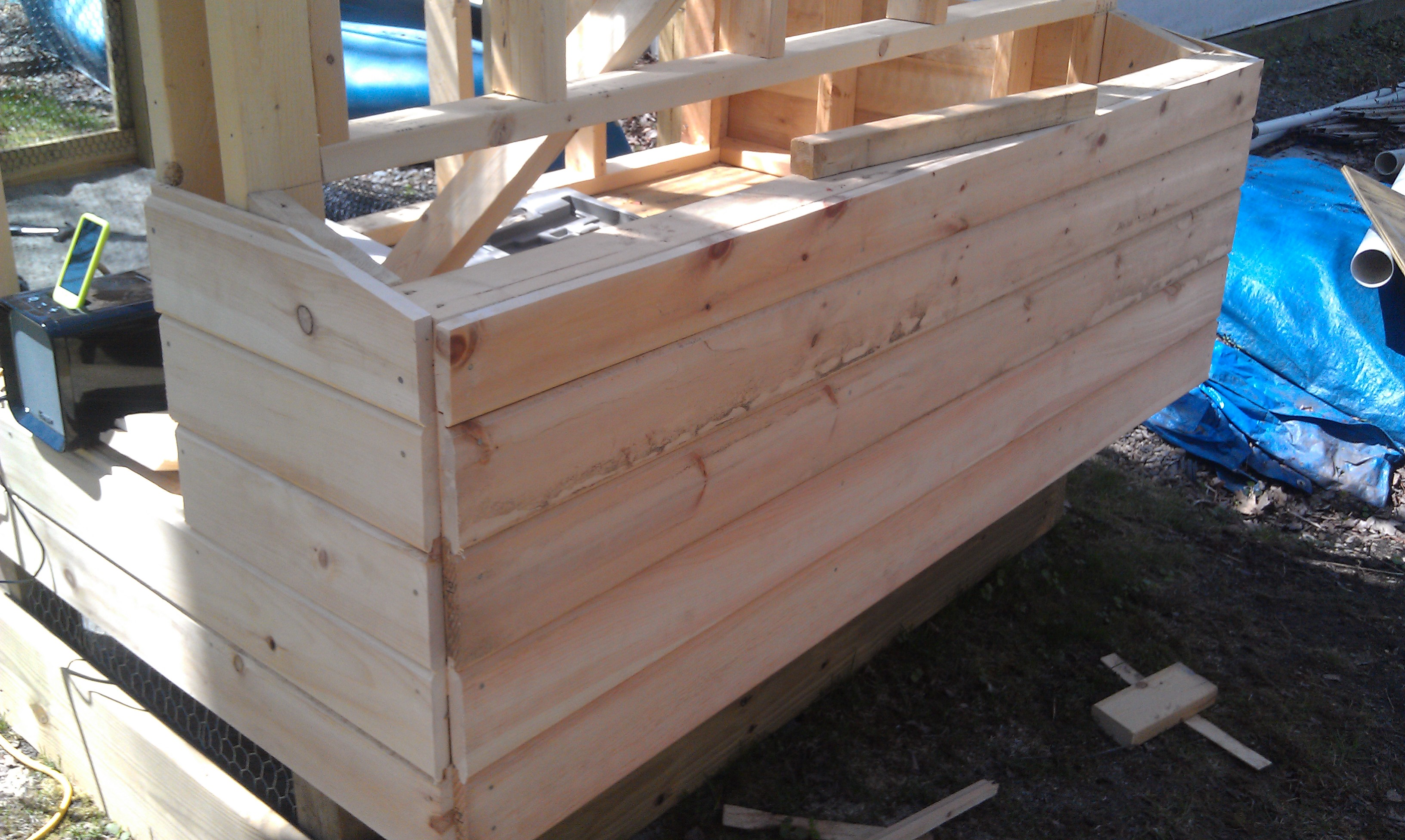 Since we were done framing, my father started covering the coop with pine boards.