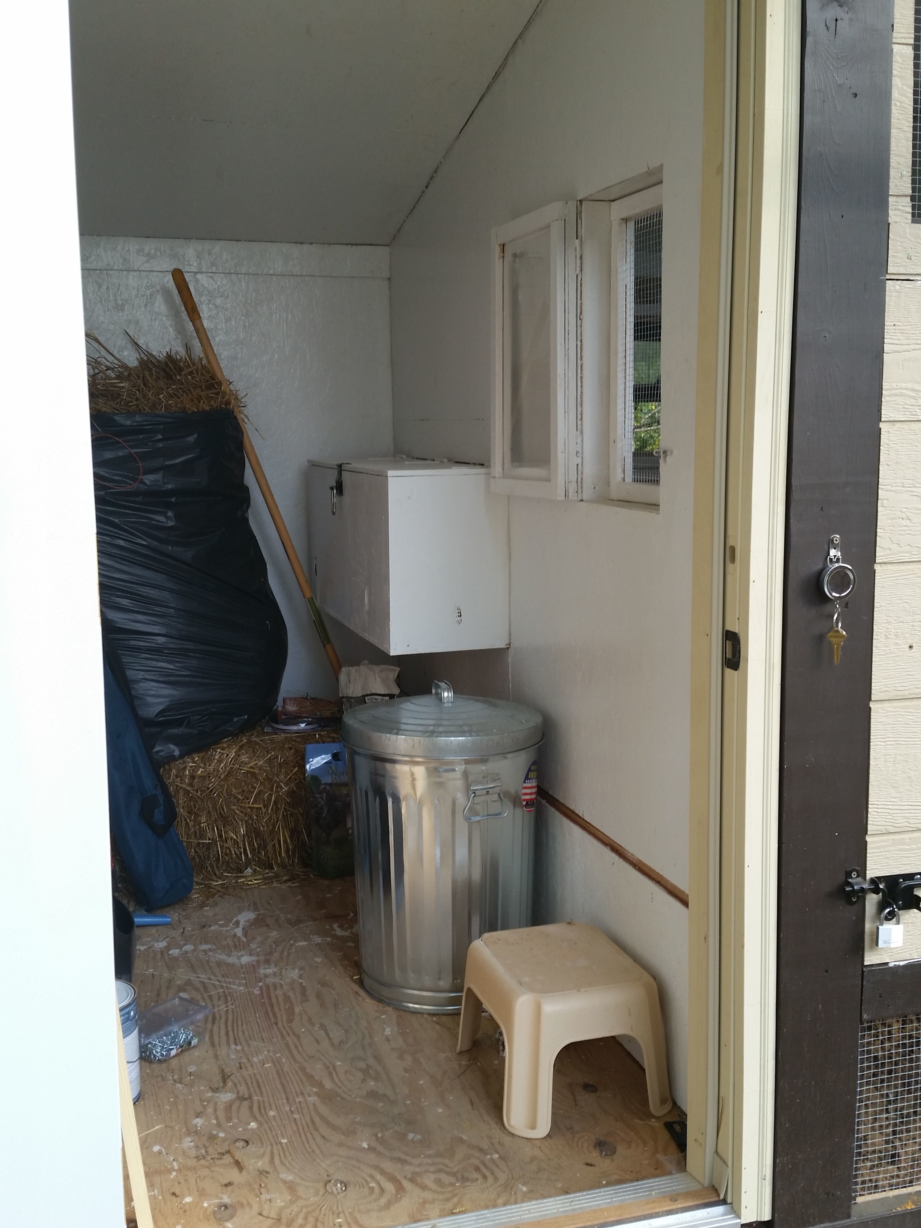 Storage portion of the coop, with nesting boxes under cover and out of the weather.  My wife insisted on being able to check on the girls from the storage/nest box area, so I cut in this little opening with one screened door and one windowed door for when it gets colder.  It actually worked well.  The week they were sequestered inside, we could just reach through to fill both the feeder and water bucket, plus offer treats since the low roost is just inside the window ledge. The retractable key ring has keys for both storage and the coop padlocks.  It's handy, and when the racoons figure how to take the keys and open the locks, it's time for us to stop raising chickens.