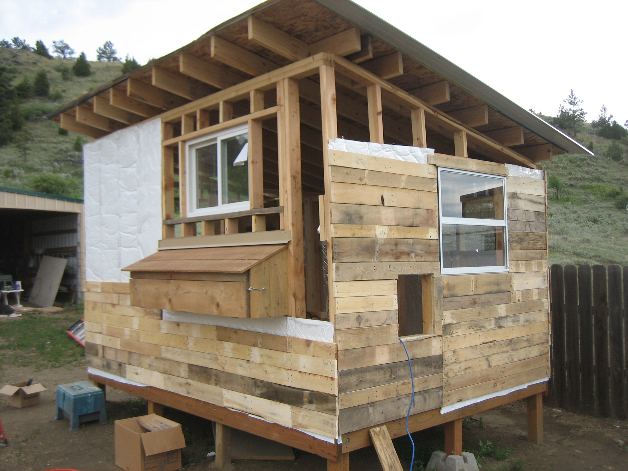 The roof is steel, also left overs from the barn.  The siding is planks pulled from free pallets that were gathered around town.  A pop door was made which can be opened from the outside for the chicks to have access to the run (when it is finished).