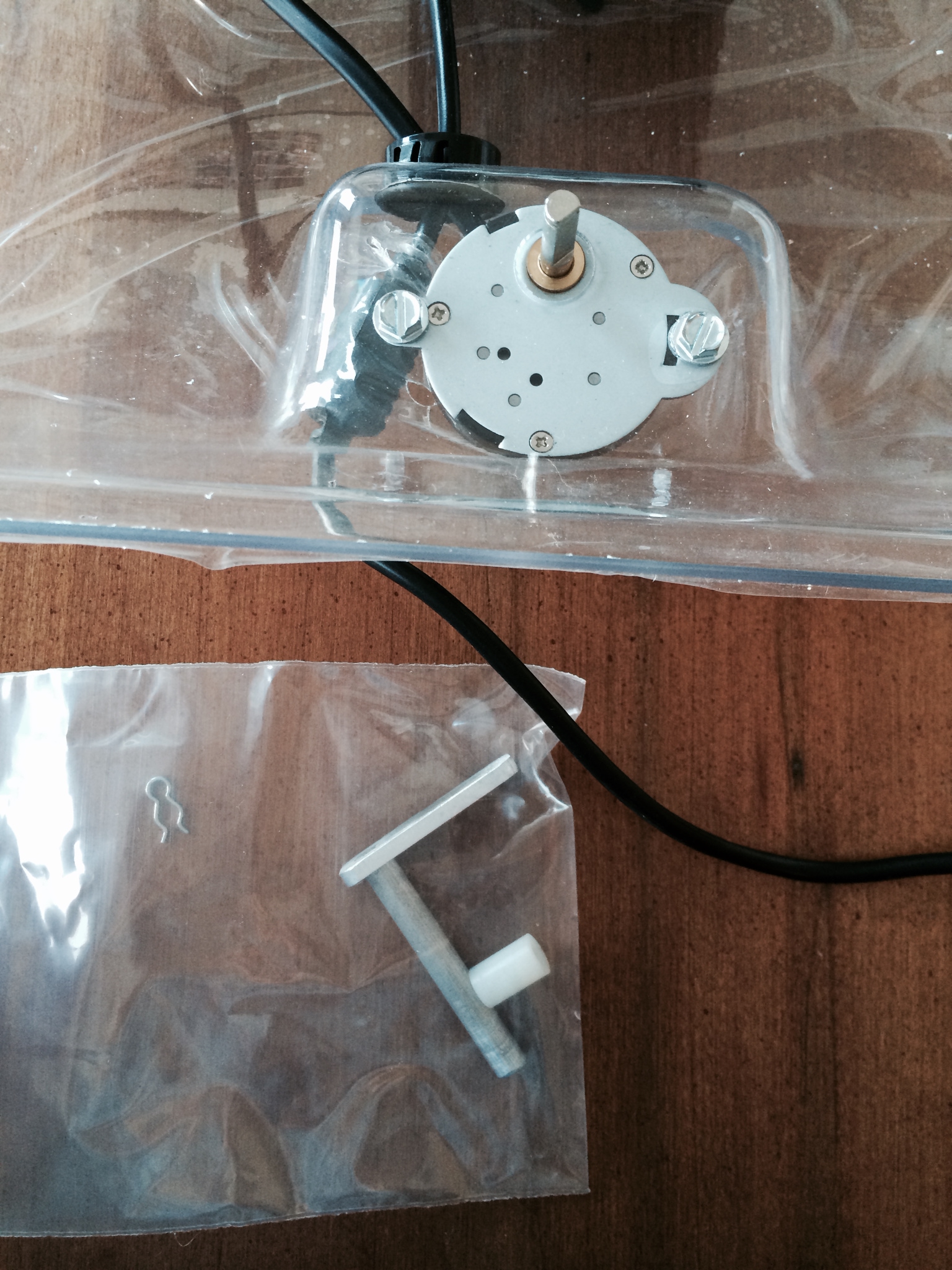 The white plastic piece goes on top of the rod sticking out of the motor. Then the metal arm (in the baggy) goes over that. Then the pin gets reattached.