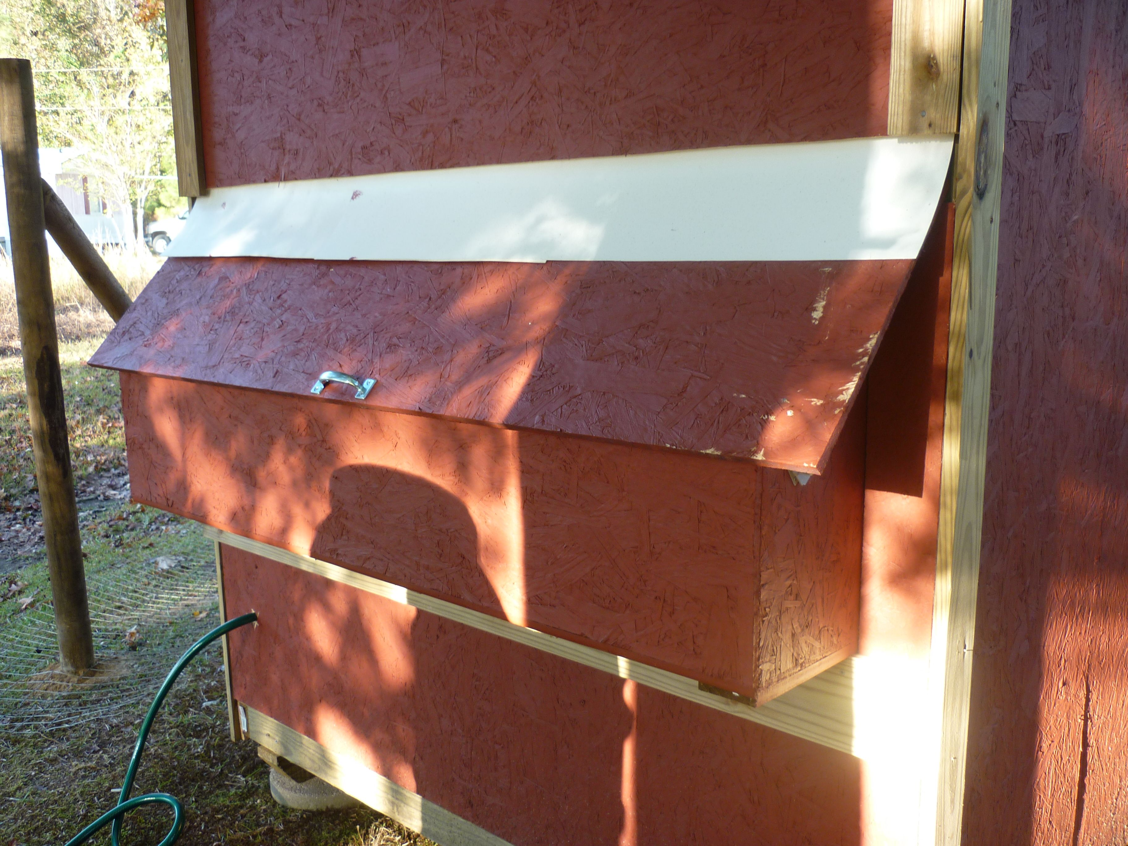 This is another view of the back of the coop.  The door can be raised to remove the eggs from the nesting boxes.  Notice the white plastic that was installed under the siding and over the door to prevent the rain from running into the nests.