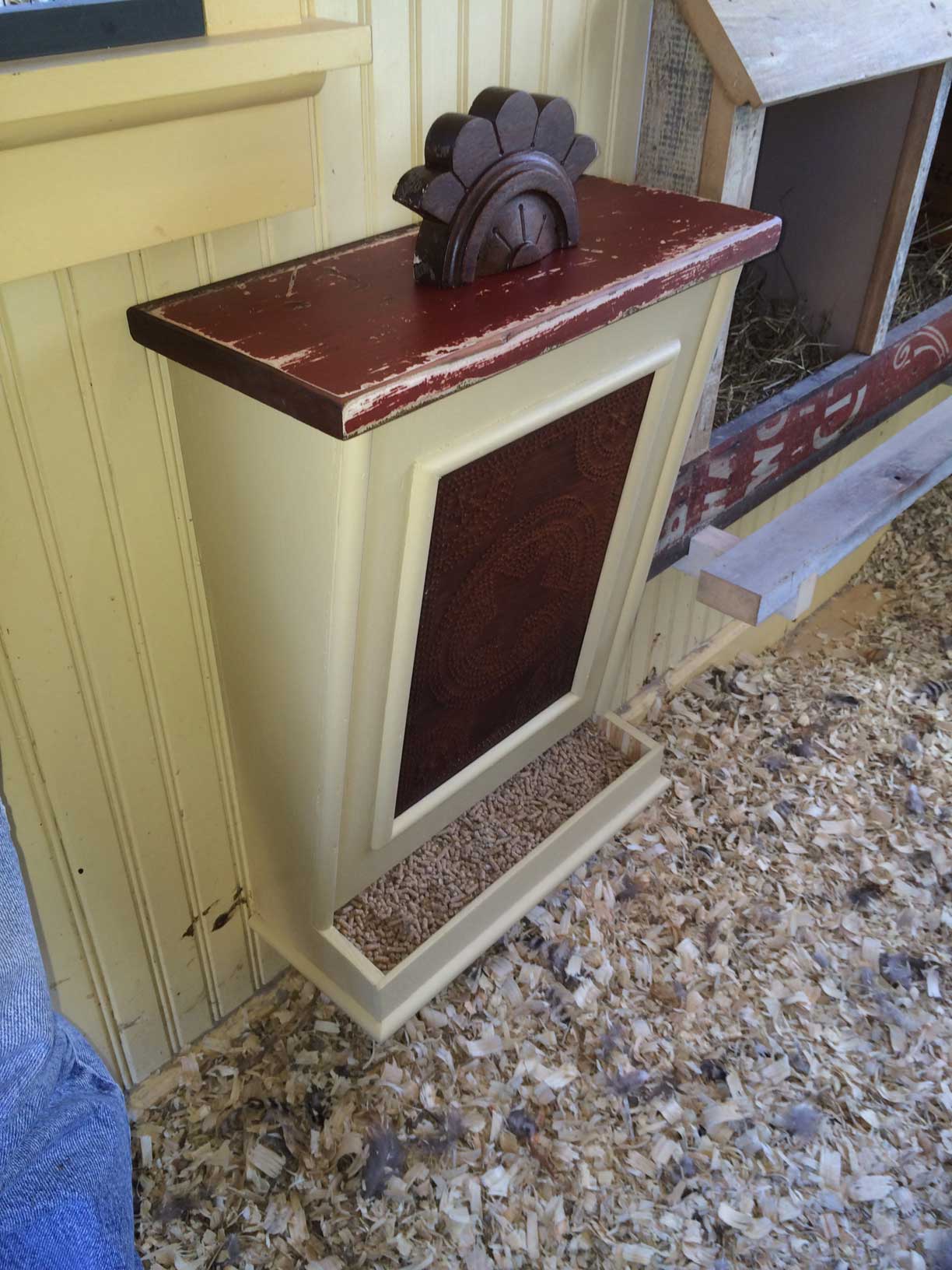 Wall mount chicken feeder. Purchased feeder shell on ebay and added trim pieces, stamped tin front, removable top (old baseboard material) with decorative handle (furniture piece).