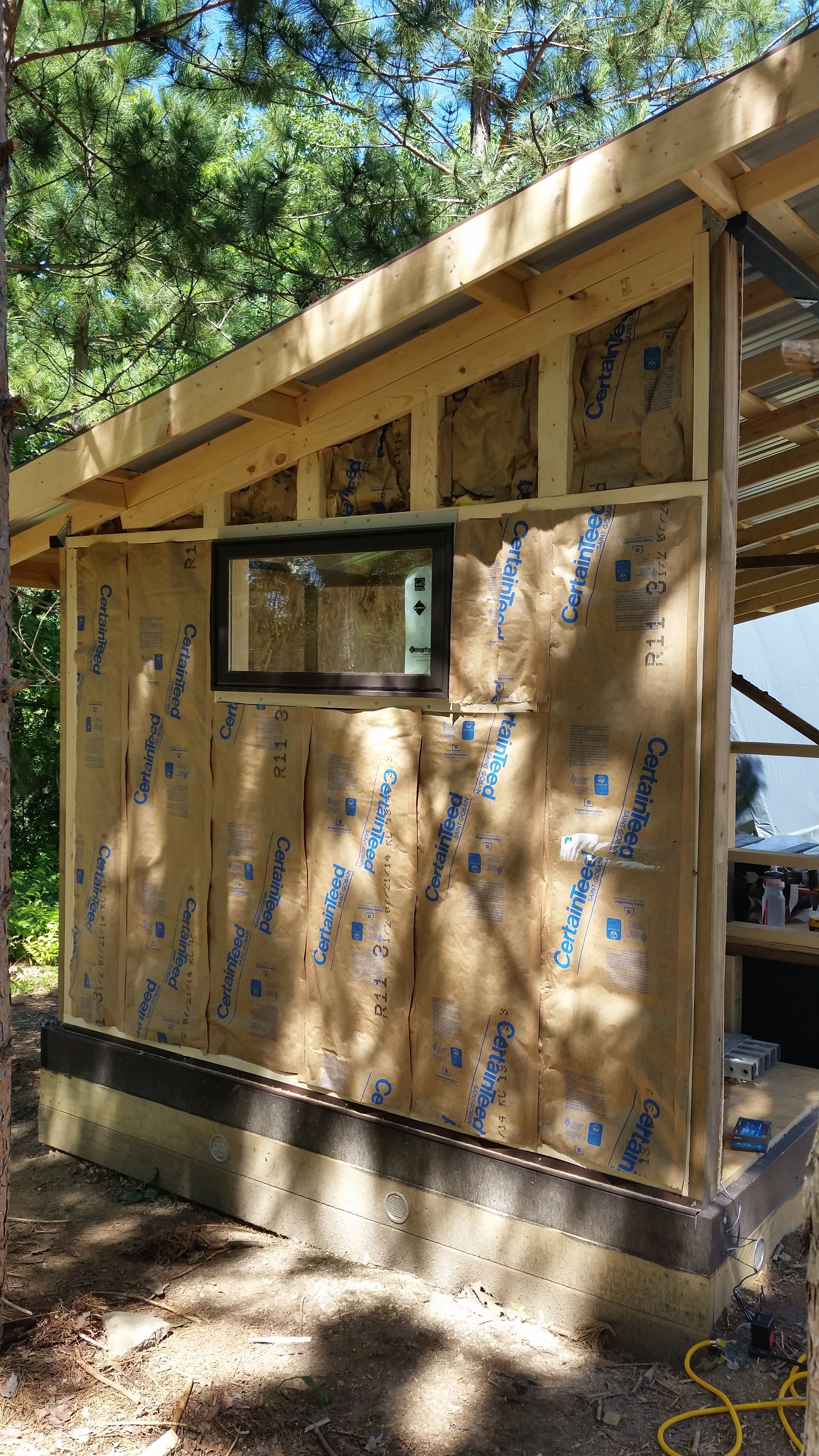 We had a crank out window left over from constructing our house basement because the contractor made the opening the wrong size.  This seemed like a perfect place to finally use it.  All the walls are packed with vapor barrier fiberglass batts, and since contractors were already here doing some insulation repair in our house, we had them spray foam the inside of the roof in both the coop and storage area.