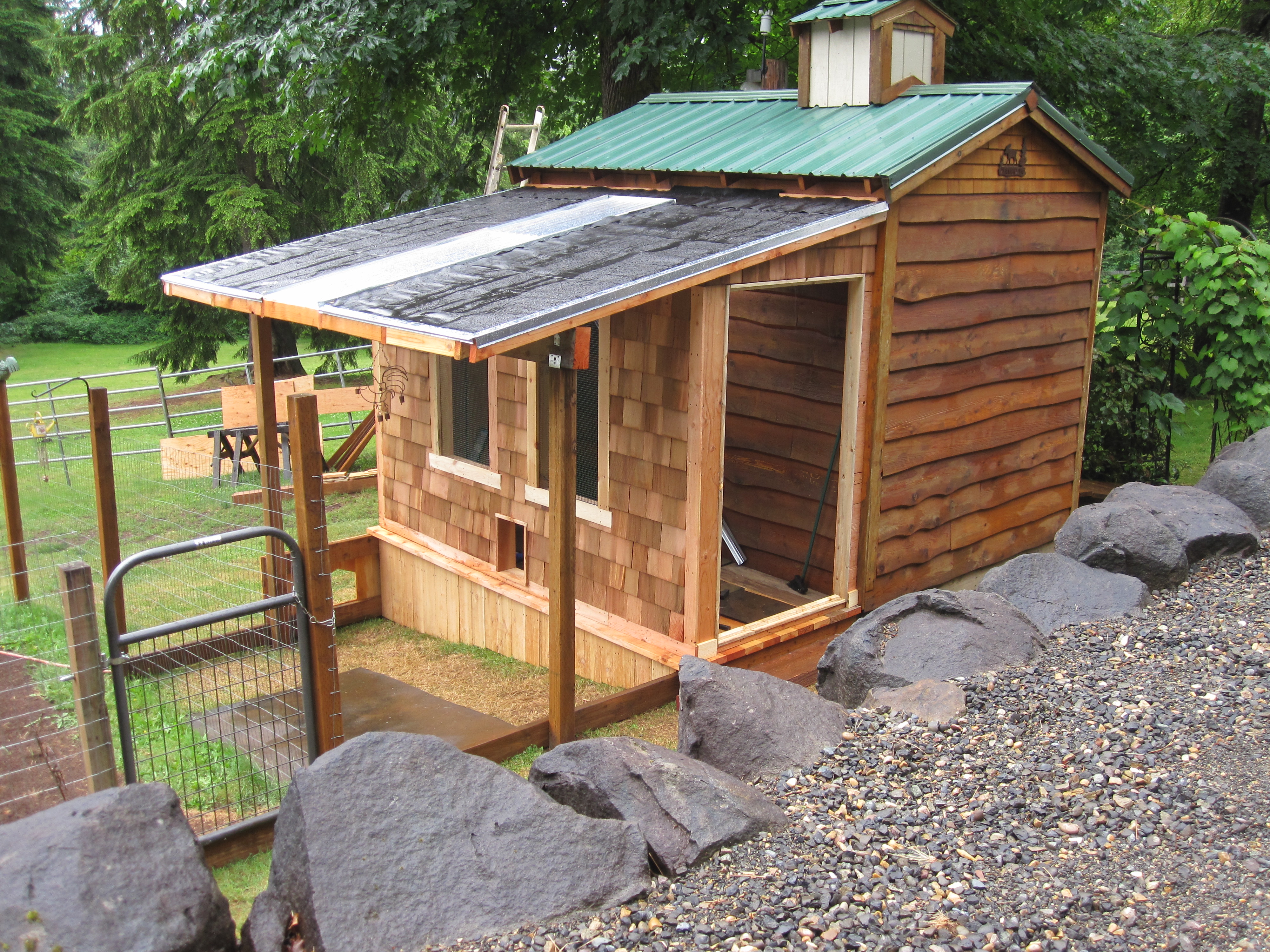 Working on the door, there is screen in the windows and the door. There will be shutters to keep the cold out when needed. The roof is green metal excluding the sky light portion and the porch will be fully enclosed with chicken wire buried in the ground.