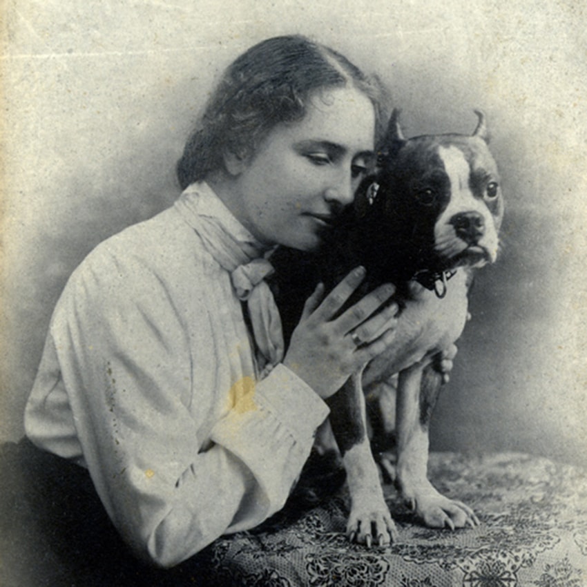 Helen Keller pressing her face against the side of small Boston bull terrier named Phiz. 