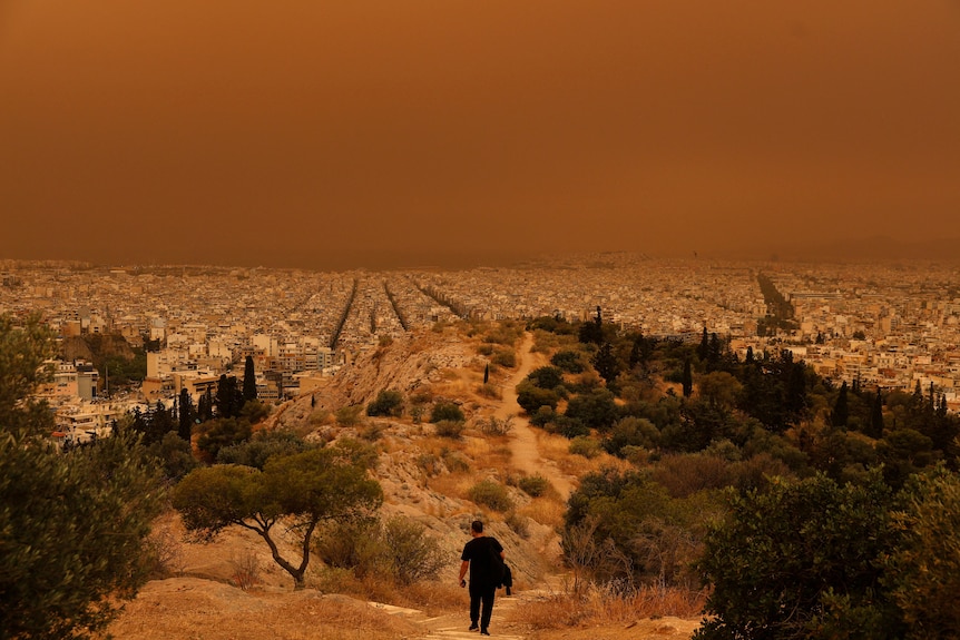A wide shot of the city of Athens that is covered in orange dust.
